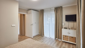 A bedroom with a bed, a wardrobe, a TV, and a bedside table. - Apartamenty Swinoujscie - Bursztyn (Swinoujscie)