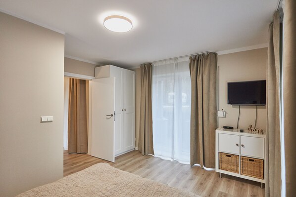 A bedroom with a bed, a wardrobe, a TV, and a bedside table.