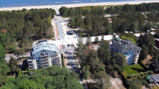 An aerial view of a coastal area with a hotel featuring a modern design, a parking lot, and a beach in the background. - Apartamenty Swinoujscie - Bursztyn (Swinoujscie)