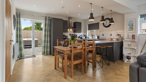 Une cuisine moderne avec des meubles en bois, un coin repas et une vue sur l’extérieur.