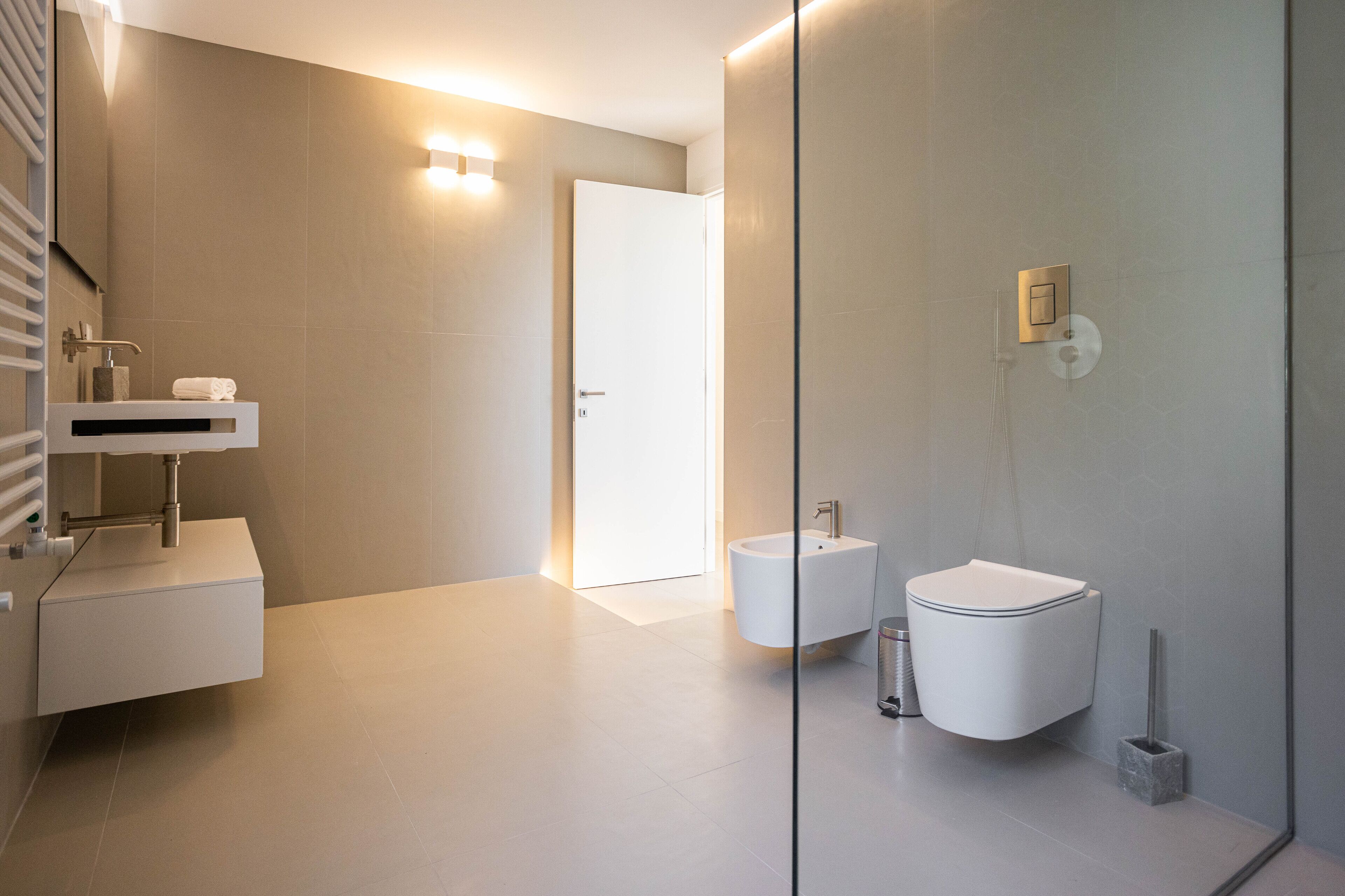 A modern bathroom with a glass shower enclosure, a white sink, and a toilet.