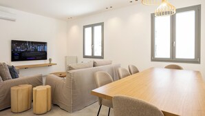Un soggiorno moderno con un divano, un tavolo da pranzo in legno e un televisore a parete.