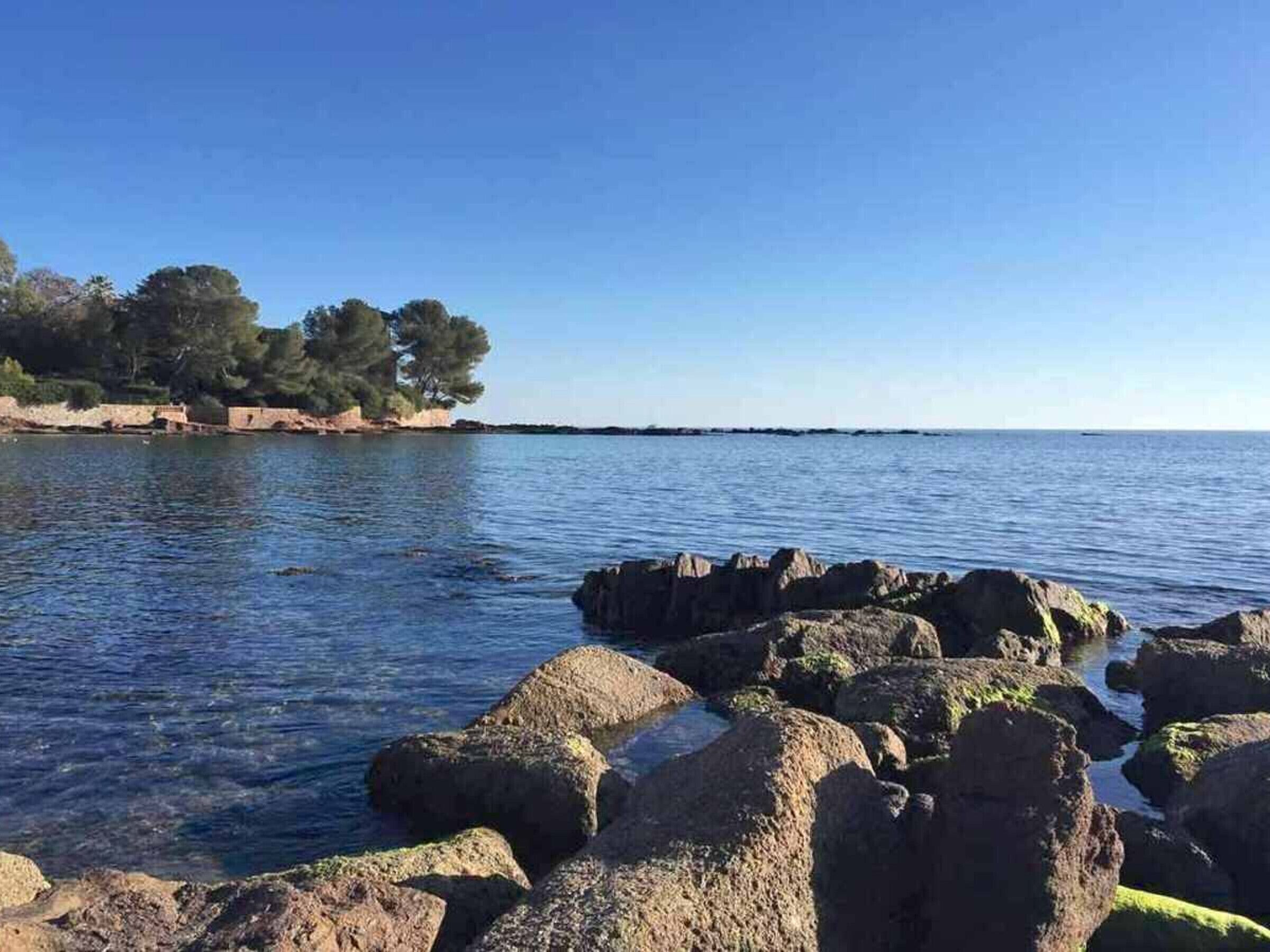 A coastal landscape with rocky formations and a clear blue sky.