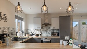 A modern kitchen with a central island, pendant lights, and a bicycle on the wall.