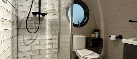 A bathroom with a glass-enclosed shower, a toilet, and a sink.