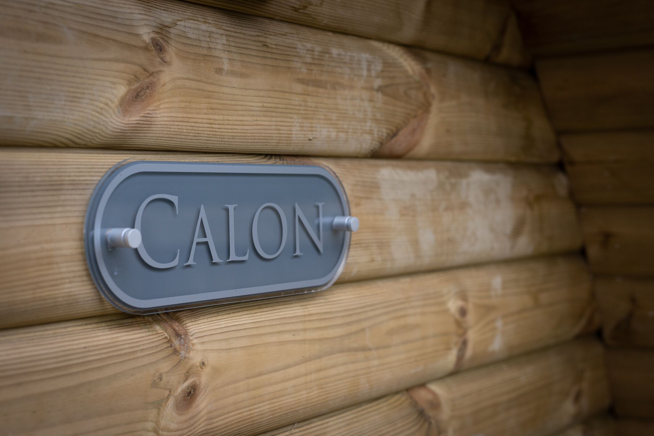 A sign with the word 'CALON' mounted on a wooden wall.