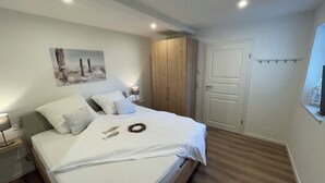 Een keurig opgemaakt slaapkamer met een bed, nachtkastjes, een garderobe en een deur.