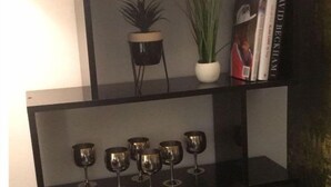 A bookshelf with books, decorative plants, and wine glasses. - Central Wigan Welcoming Townhouse Sleeps up to 6 (Wigan)
