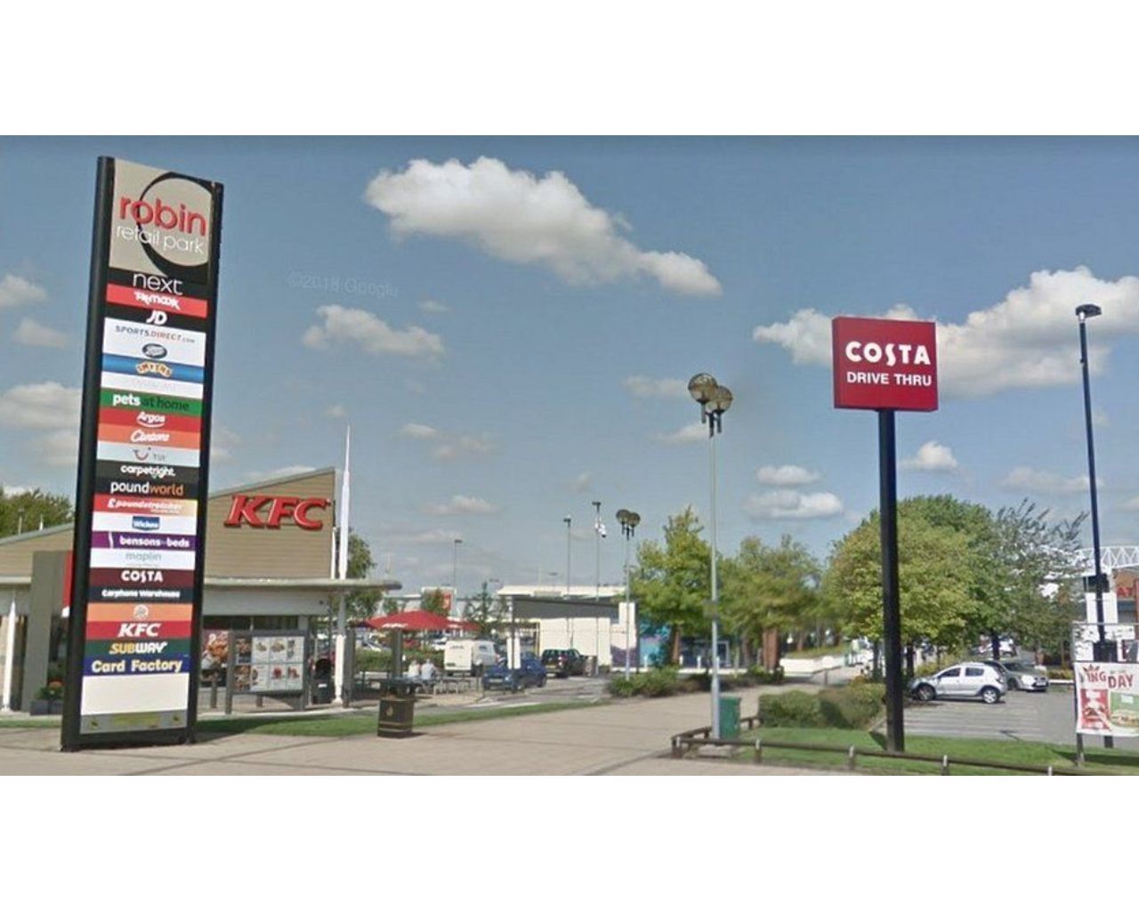 A KFC restaurant with a signboard listing various brands like Robin, Next, and Costa.