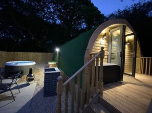 A cozy outdoor hot tub area with a wooden deck, a hot tub, and a seating area. - Cwtch (Tenby)