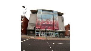 Un bâtiment moderne doté d’une grande façade en verre et d’une imposante fresque murale rouge.