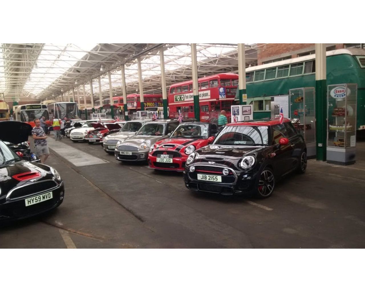 Exposición de automóviles con diversos modelos en exhibición, incluyendo un Mini Cooper negro y un Mini Cooper rojo.
