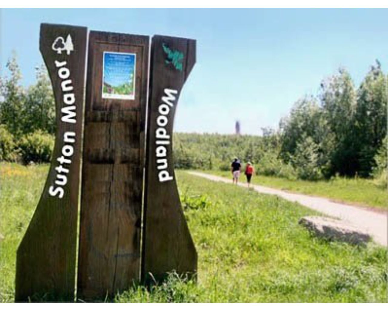 A wooden signpost with 'Sutton Manor' and 'Pulpum' directions, a path, and two people walking.