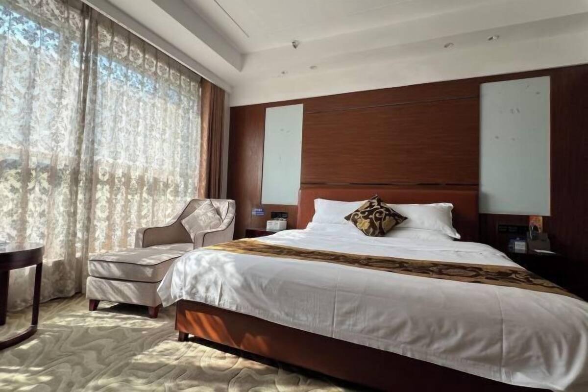 Une chambre d’hôtel avec un grand lit, une chaise, une petite table et une vue sur l’extérieur.