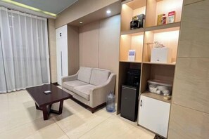 Un espace de vie comprenant un canapé, une table basse, un petit meuble et un réfrigérateur.