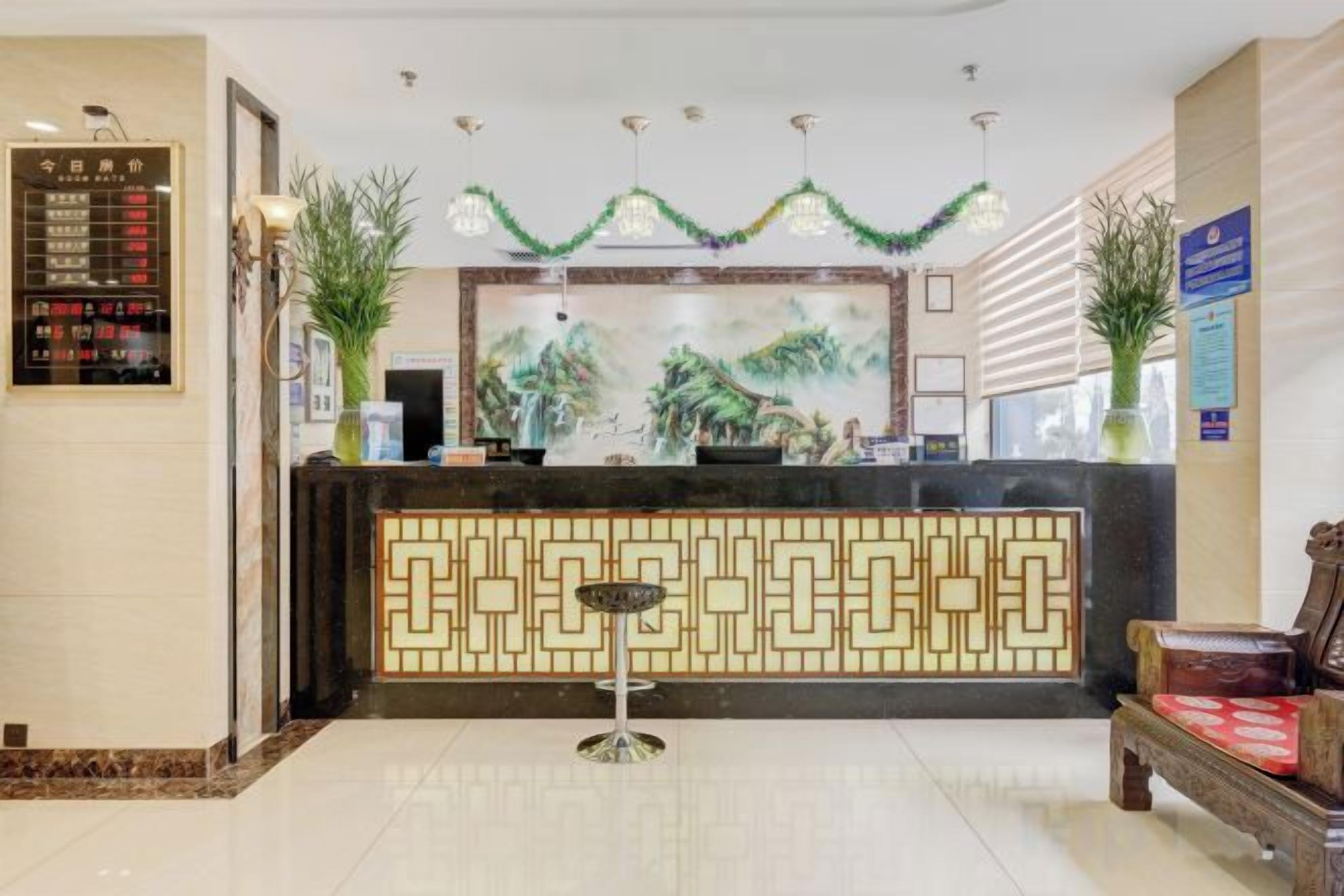 A hotel reception area with a reception desk, a seating area, and a decorative wall.