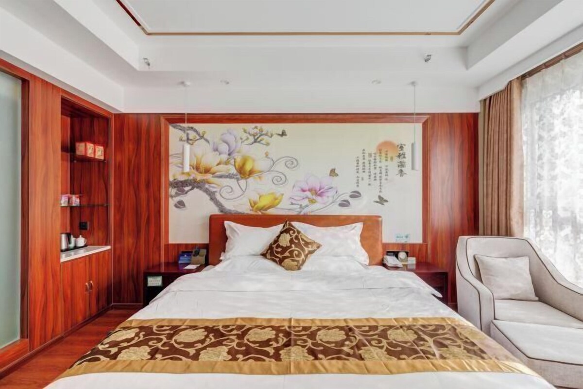 Une chambre d’hôtel avec un grand lit, une armoire en bois et une fresque murale décorative.