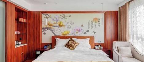 A hotel room with a large bed, wooden wardrobe, and a decorative wall mural.