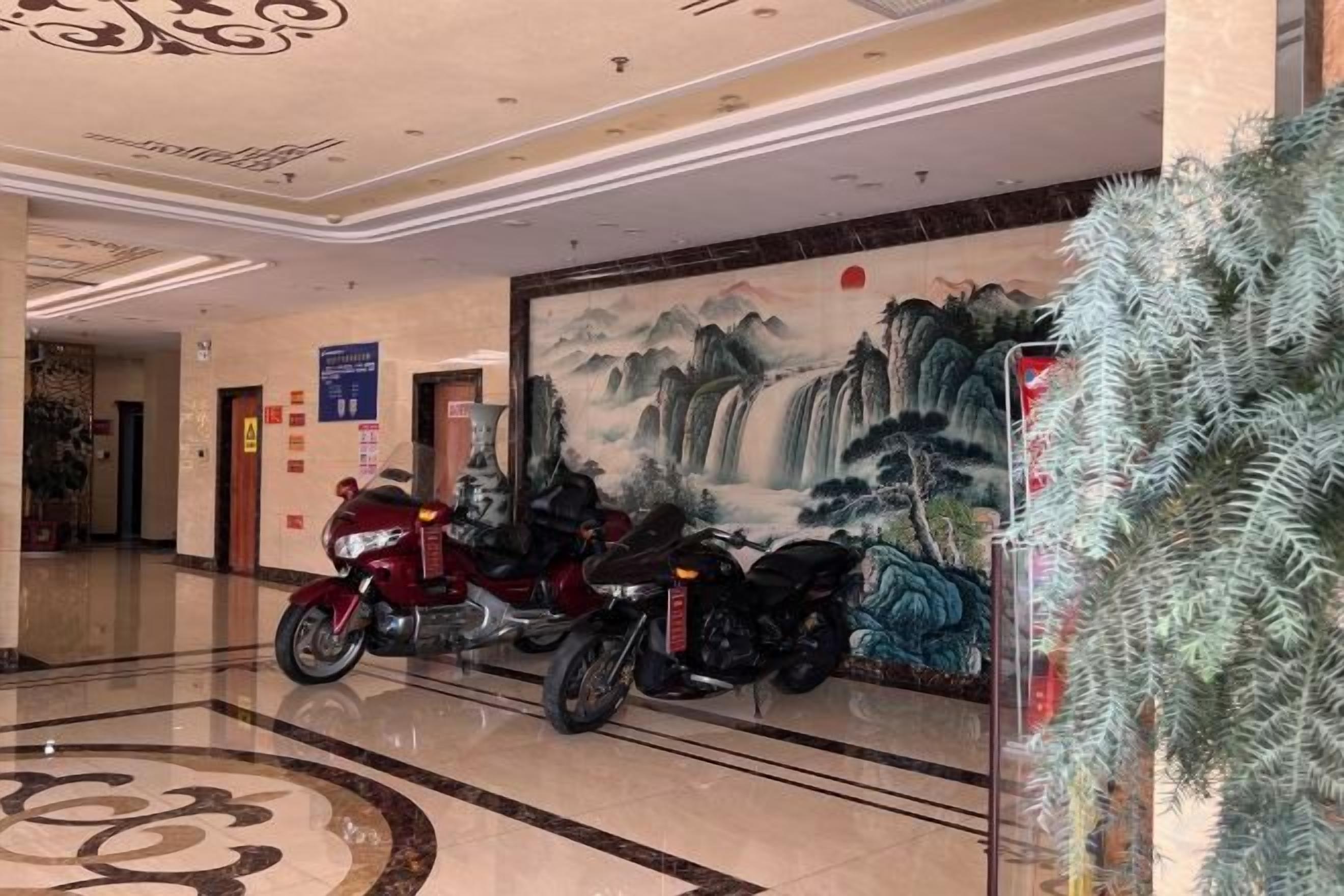 A hotel lobby with a mural, two motorcycles, and a decorative plant.