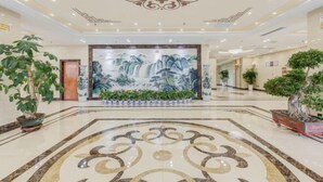 A spacious lobby with a large mural, potted plants, and a marble floor. - Gaoqing Shuangchuangyuan Hotel (Gaoqing)