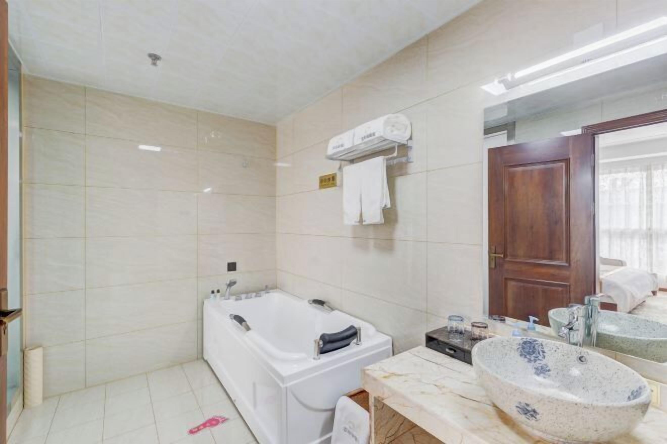 A bathroom with a bathtub, a sink with a marble countertop, and a mirror.