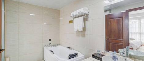 A bathroom with a bathtub, a sink with a marble countertop, and a mirror.