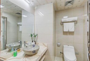 Une salle de bain avec un meuble-lavabo en marbre, un lavabo agrémenté d’un récipient décoratif, un miroir, un porte-serviettes et des toilettes.