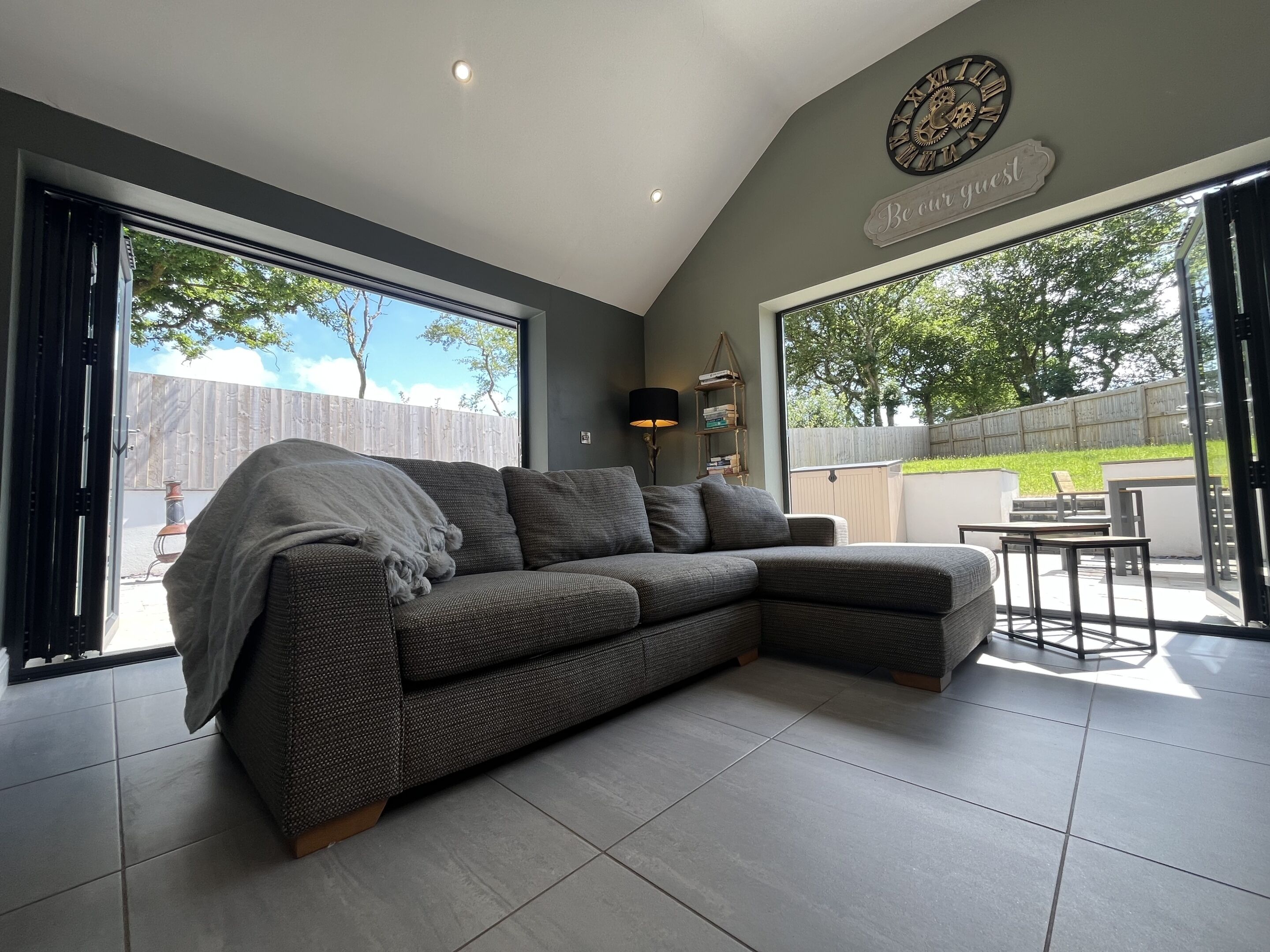 A modern living room with a sectional sofa, a dining area, and a large window offering a view of the outdoors.