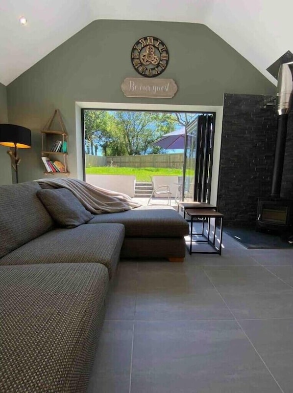 A modern living room with a large sofa, a fireplace, and a view of the outdoors.