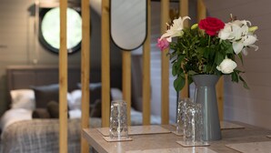 Una habitación de hotel con una cama, una mesita de noche con un florero y un espejo en la pared.
