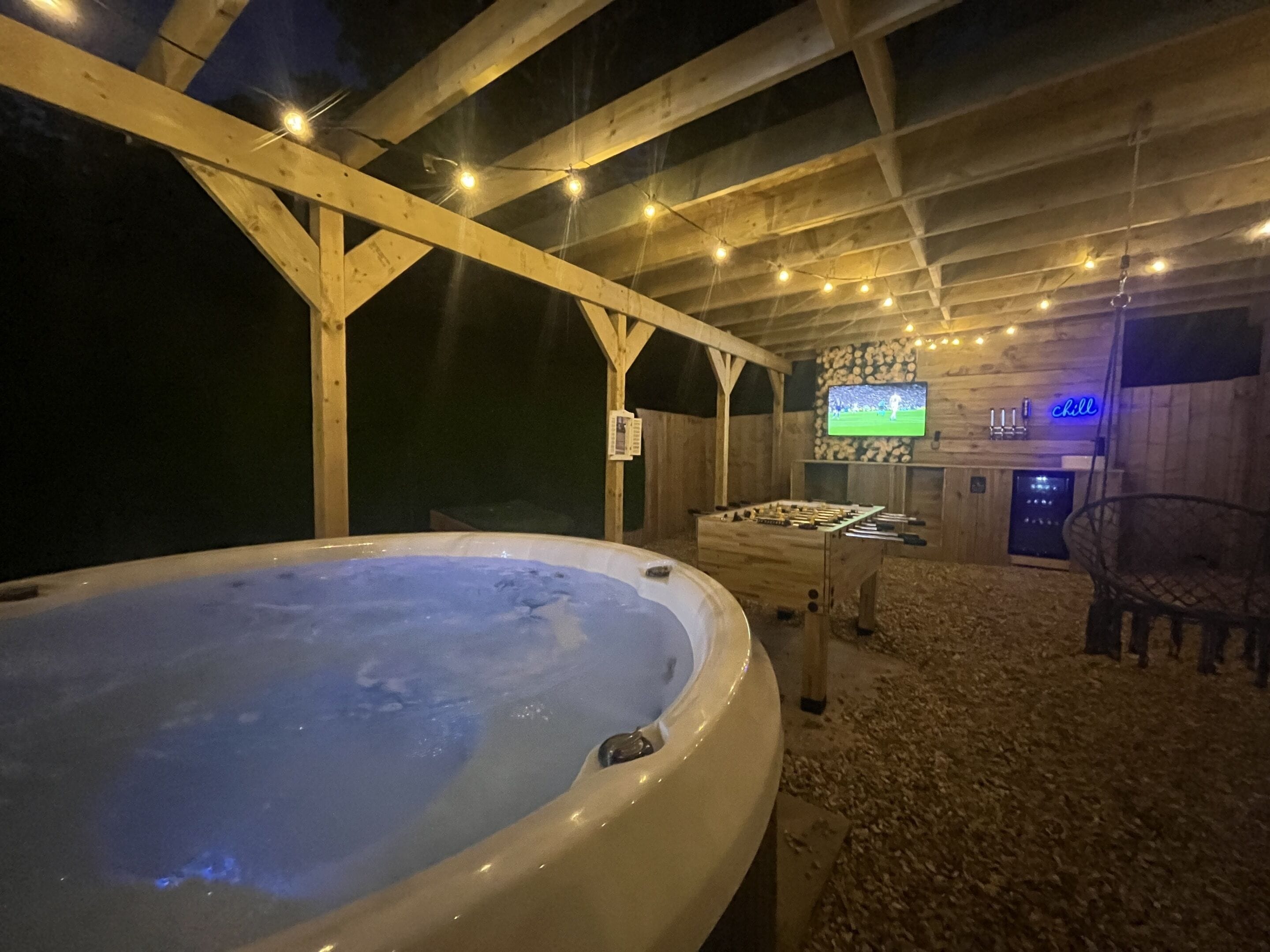 A hot tub in a wooden room with a television and a bar area.