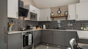 A modern kitchen with grey cabinets, a built-in oven, a microwave, and a coffee maker.