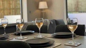 A dining area with a table set for four, each with a wine glass and a plate.