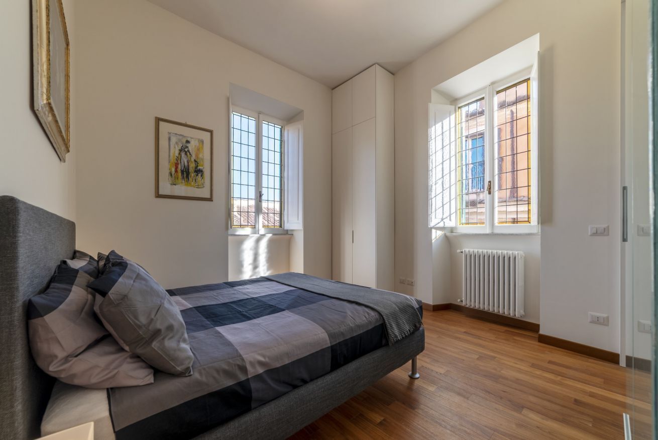 A bedroom with a bed, a radiator, and a window.