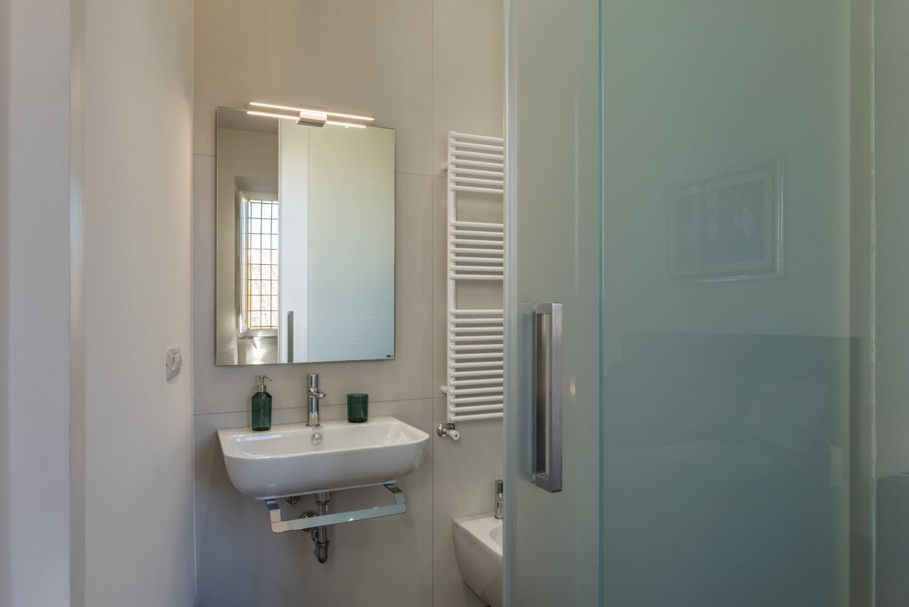A modern bathroom with a white sink, mirror, and towel rack.