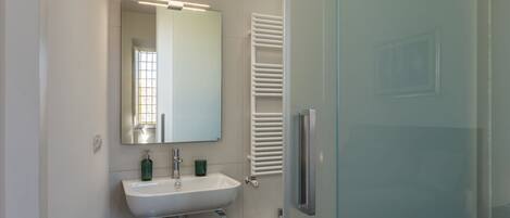 A modern bathroom with a white sink, mirror, and towel rack.