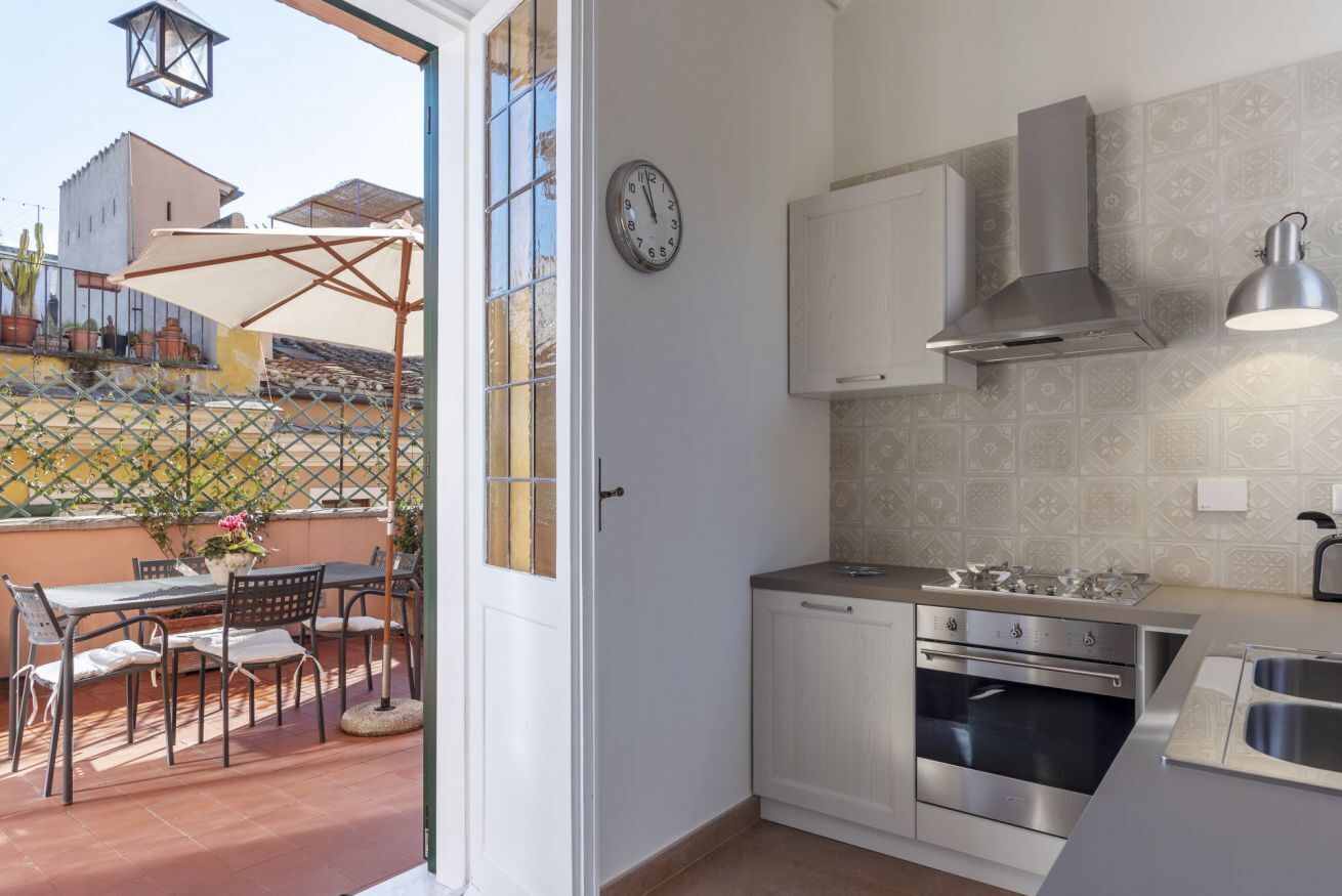 A compact kitchen with white cabinets, a stainless steel range hood, and a built-in oven.