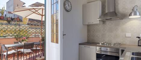 A compact kitchen with white cabinets, a stainless steel range hood, and a built-in oven.