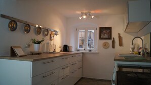 A compact kitchen with white cabinets, a wooden countertop, and a window with a view. - The Jura House 1540 - a vacation in a monument on the Danube Cycle Path (Pförring)
