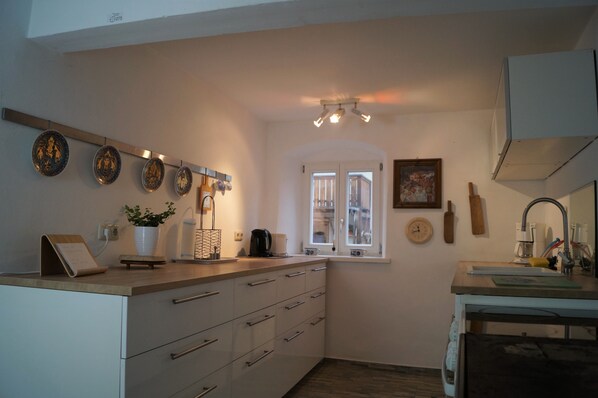 A compact kitchen with white cabinets, a wooden countertop, and a window with a view.