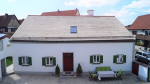 A white building with a red door, green shutters, and a tiled roof. - The Jura House 1540 - a vacation in a monument on the Danube Cycle Path (Pförring)