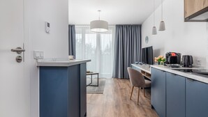 Uma cozinha moderna com uma ilha central, uma área de refeições com uma cadeira e uma janela grande com cortinas.