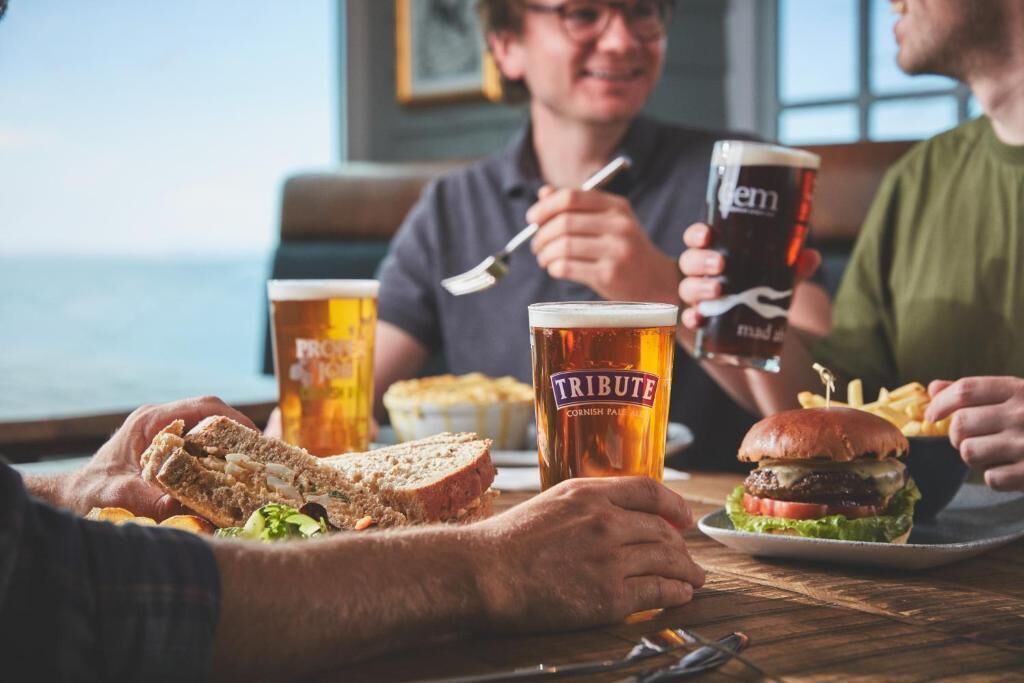 A dining table with food, drinks, and people.