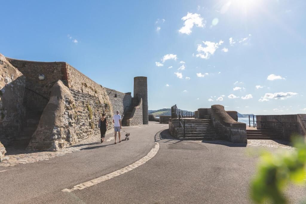 A coastal fortification with stone walls and a paved walkway.