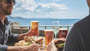 Two people sitting at a wooden table with various beers and sandwiches. - Rock Point Inn (Lyme Regis)