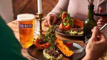 Een eettafel met een glas bier, een kaars en een bord eten.