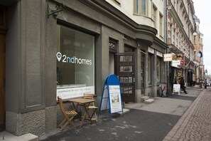 A 2ndhomes storefront with a large window, a small outdoor seating area, and a blue signboard. - Superb 1BR home with sauna and terrace (Helsinki)