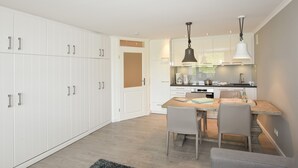 Una cucina moderna con pensili bianchi, un tavolo da pranzo in legno e due lampade a sospensione.