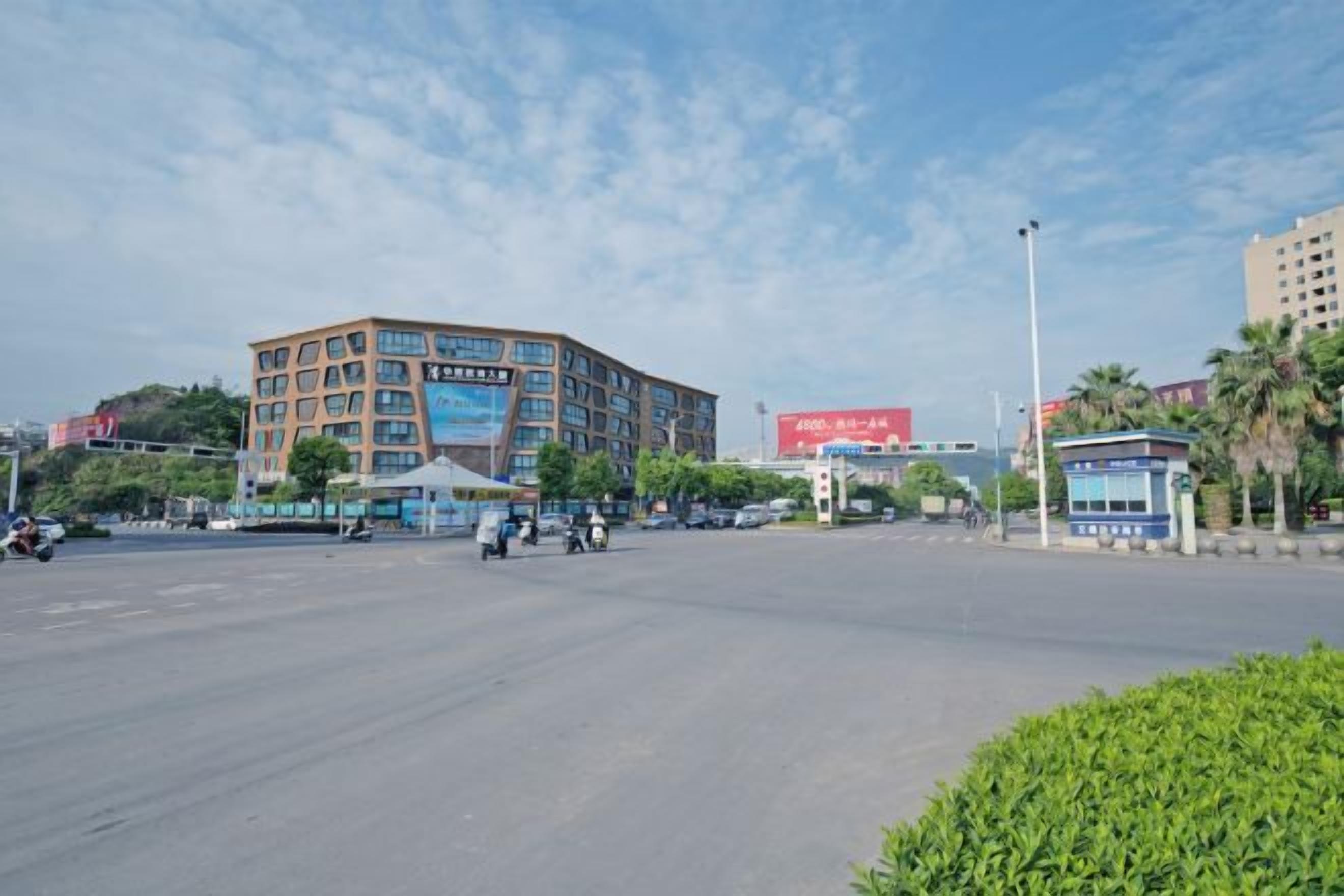 A multi-story building with a commercial sign on the side, a clear sky, and a road with vehicles.