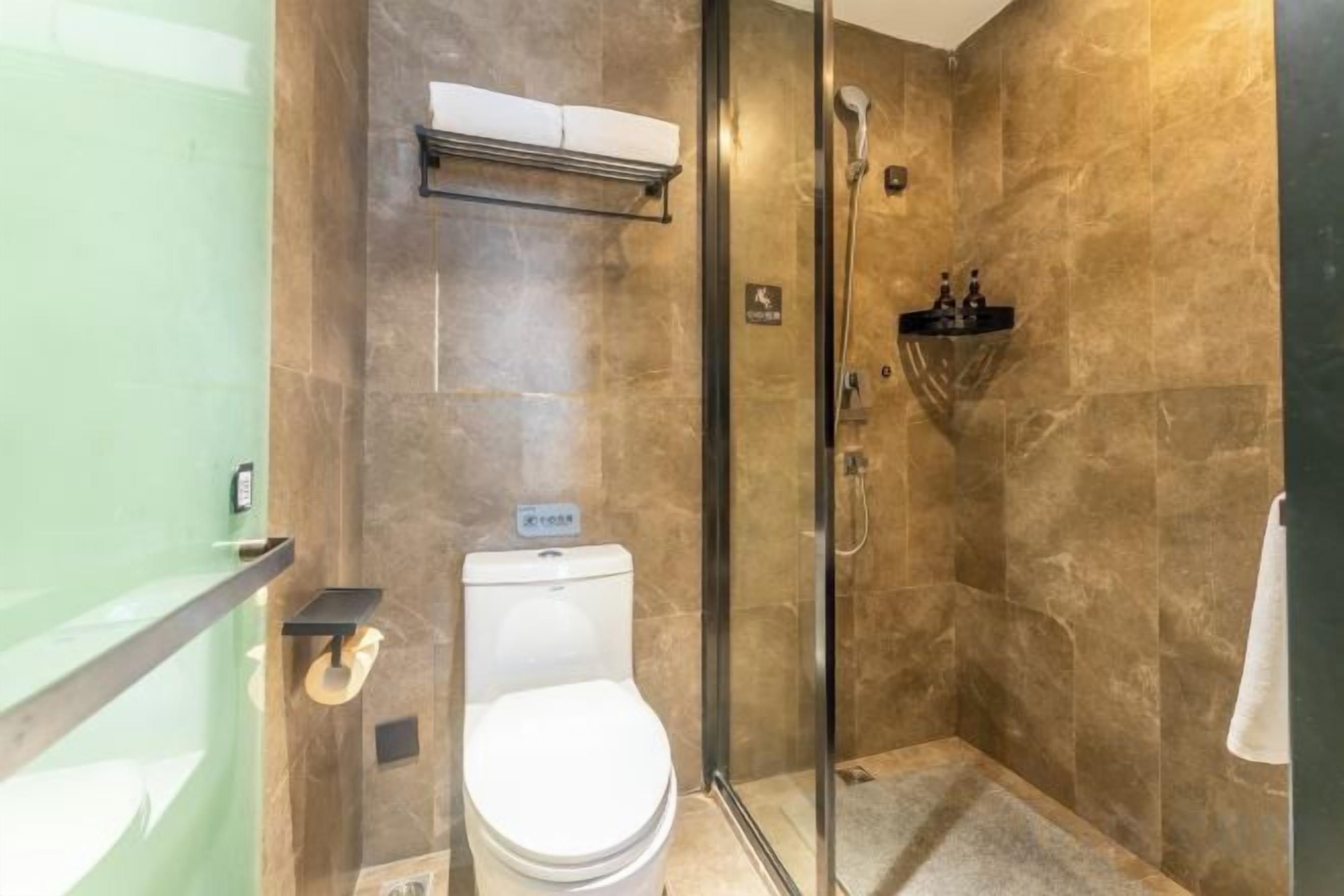 A bathroom with a glass-enclosed shower, a toilet, and a towel rack.